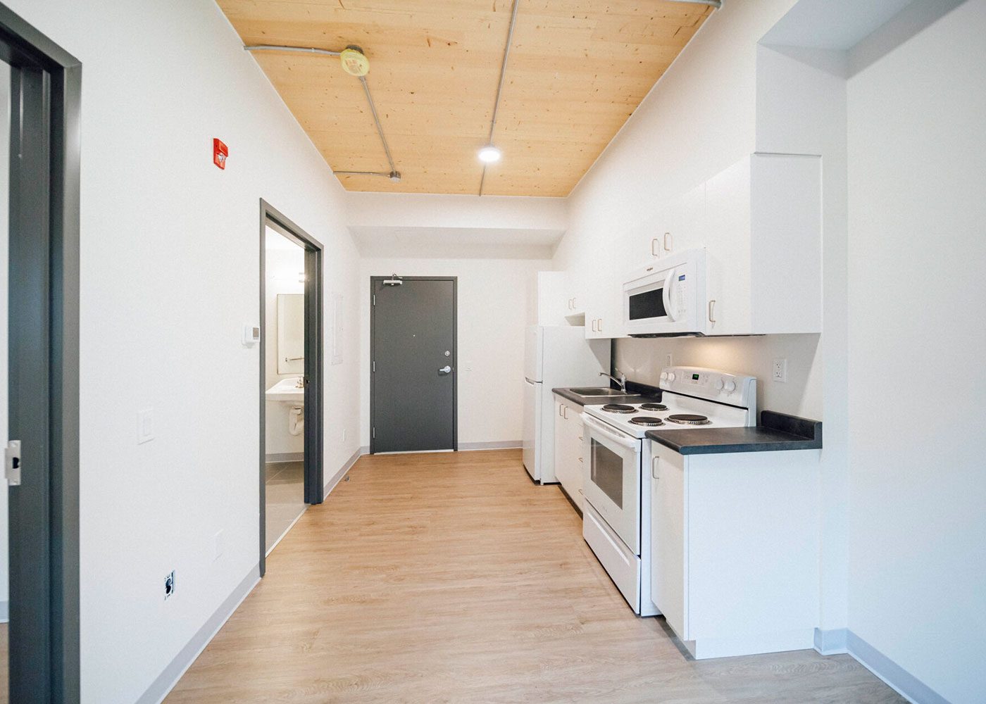 Suite kitchen and hallway beneath an exposed timber ceiling