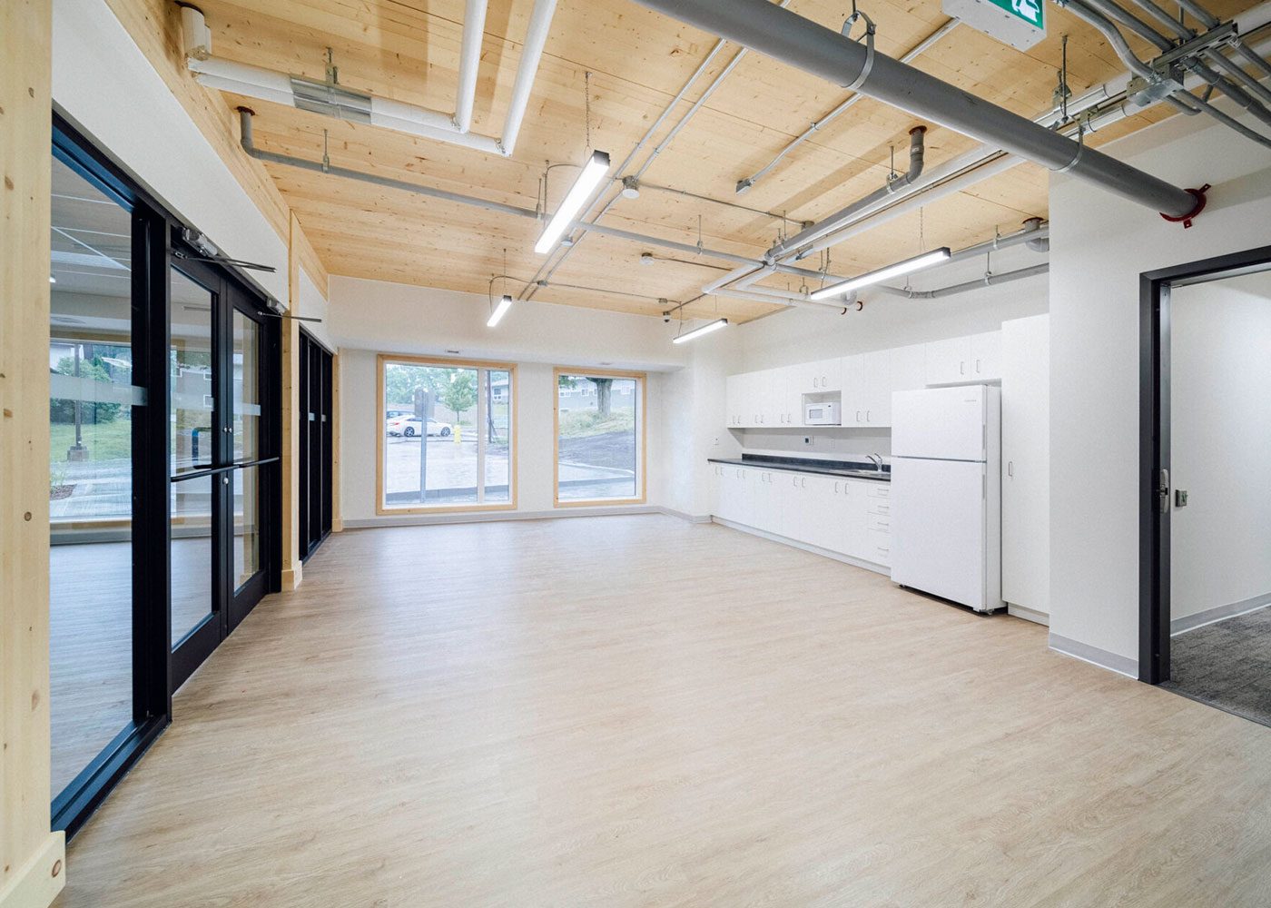 Common room with kitchen, large windows and exposed timber ceiling
