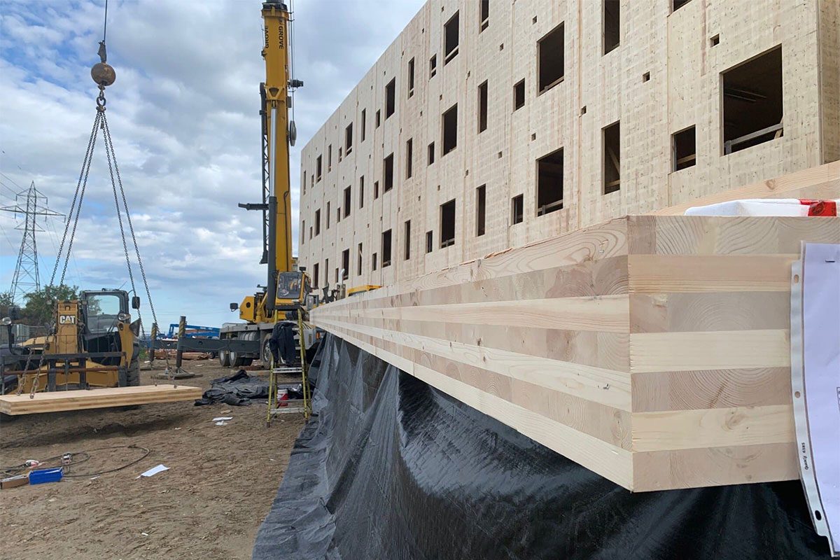 Crane lifting a cross-laminated timber panel into place