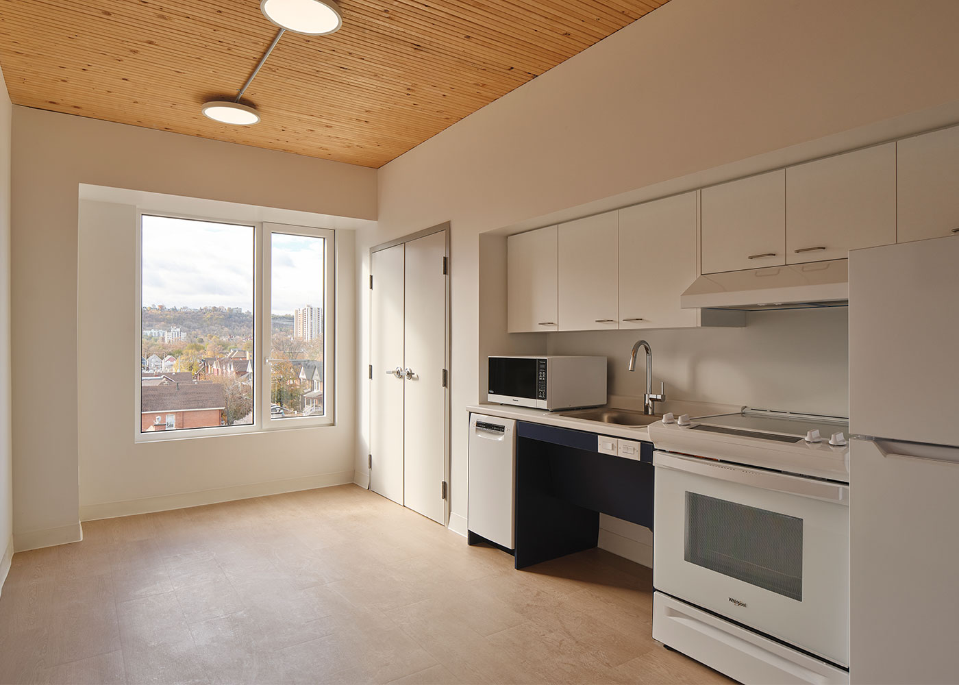 Completed suite with compact kitchen, large window and exposed timber ceiling