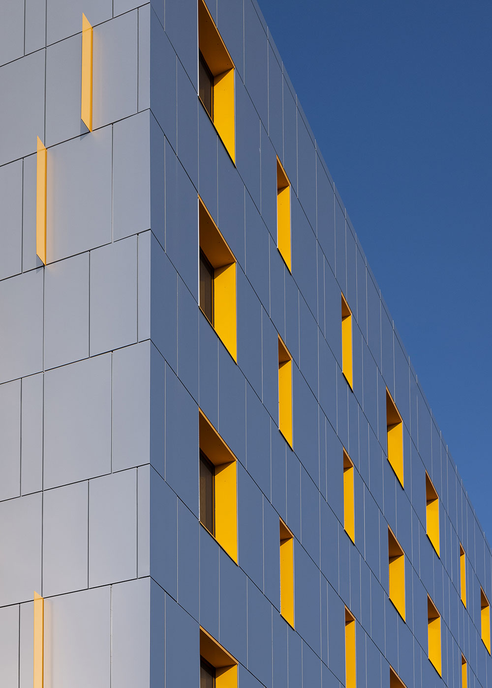 Façade detail with yellow window reveals against a clear sky